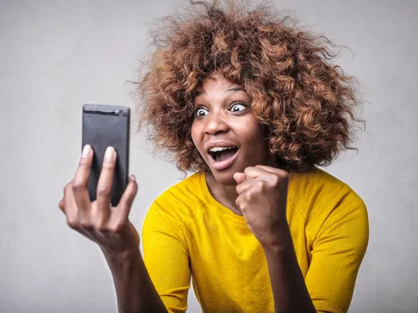 Persona reaccionando con sorpresa y alegría a una notificación en el móvil