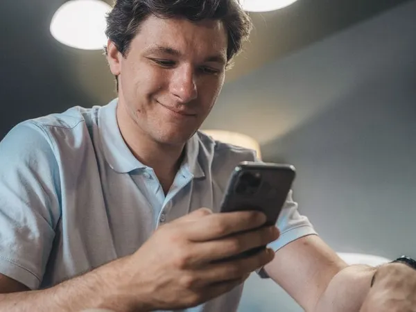 Persona sonriendo al recibir una respuesta instantánea en el móvil